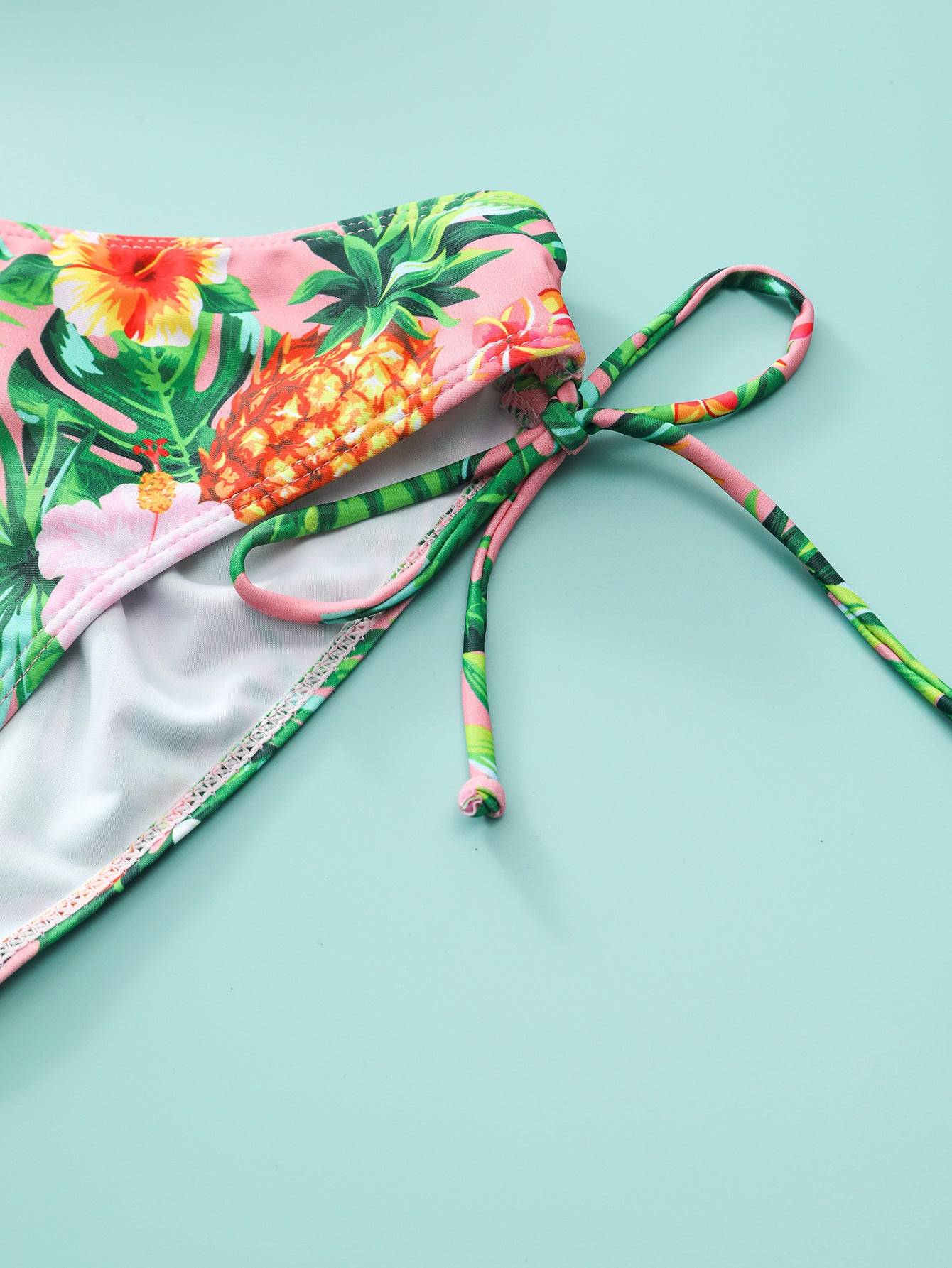 Детайл от долнището на бански ''Reflection'' в розово с флорални мотиви. Връзки отстрани позволяват регулиране за комфортно носене.